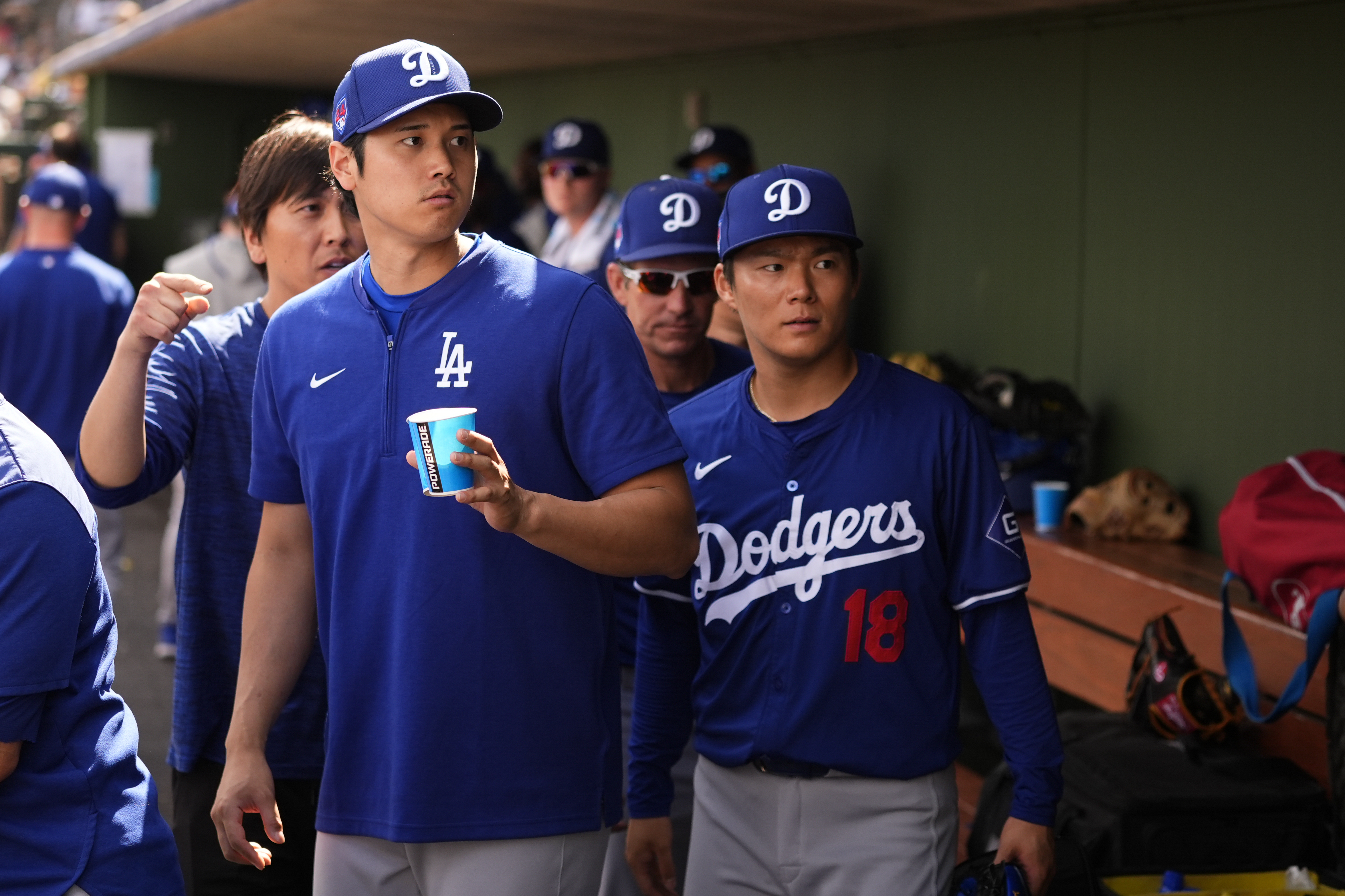 Los Angeles Dodgers designated hitter Shohei Ohtani, left, and starting pitcher Yoshinobu Yamamoto (18) look on in the dugout during a spring training baseball game against the Texas Rangers, Wednesday, Feb. 28, 2024, in Surprise, Ariz. (AP Photo/Lindsey Wasson)